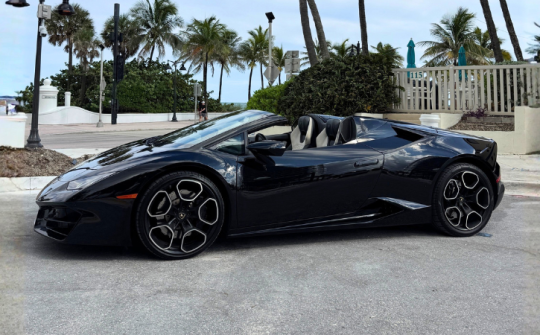 Black Lamborghini Huracán Spyder convertible parked near the beach available for exotic car rental in Miami through Dream Exotics Miami