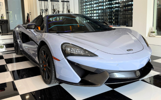 Light blue McLaren 570 convertible luxury rental displayed indoors at Dream Exotics Miami exotic car collection